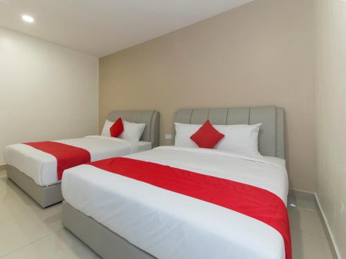 two beds with red pillows in a bedroom at Hotel Agro in Raub