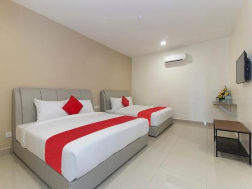 2 camas en una habitación de hotel con sábanas rojas y blancas en Hotel Agro en Raub