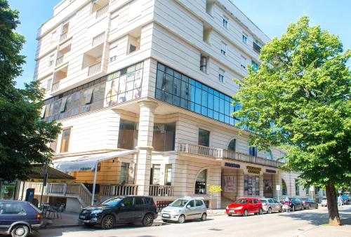 a large white building with cars parked in front of it at Yellow Lily Mostar Apartman in Mostar