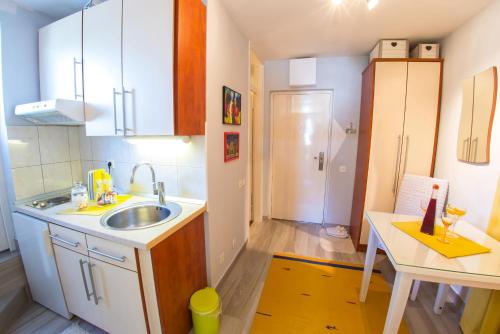 a small kitchen with a sink and a table at Yellow Lily Mostar Apartman in Mostar