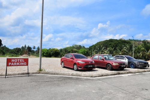 three cars parked in a parking lot with a hotel parking sign at Hotel Agro in Raub