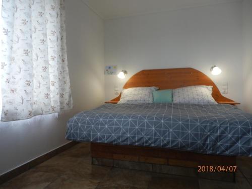 Schlafzimmer mit einem Bett mit einem Kopfteil aus Holz und Vorhängen in der Unterkunft Flóra Vendégház Tass in Tass