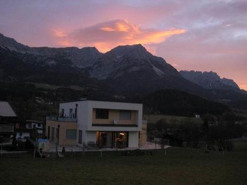 a house in a field with mountains in the background at Appartement Hoschek in Scheffau am Wilden Kaiser