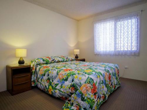 a bedroom with a bed with a colorful comforter and a window at Seabreeze 6 in Tuncurry