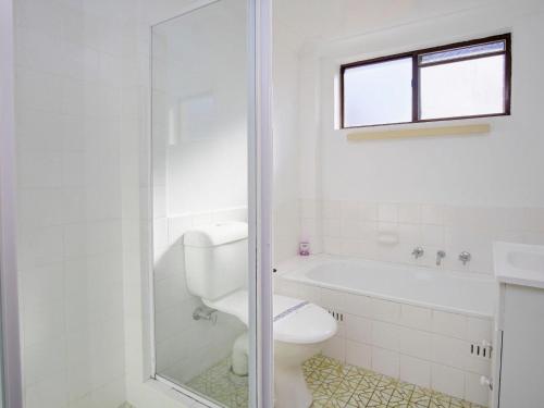 a white bathroom with a toilet and a shower at Seabreeze 6 in Tuncurry