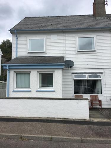 a white house with a bench in front of it at Lochalsh View, Kyle, 1 Mile to Skye in Kyle of Lochalsh