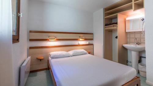a small bedroom with a bed and a sink at Vacancéole - Résidence Les Gorges Rouges in Guillaumes