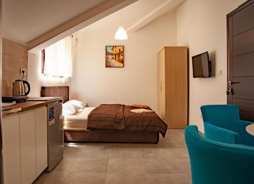 a bedroom with a bed and a kitchen with a blue chair at Rooms & Apartments Vukasović in Kotor