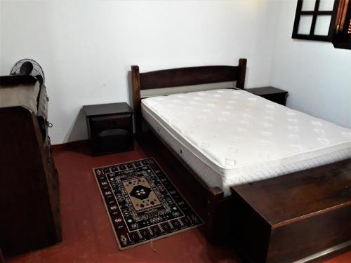a bedroom with a bed and two tables and a rug at Recanto do Ribeirão in Pindamonhangaba