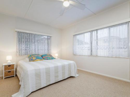 a white bedroom with a bed and two windows at Wyvern in Forster