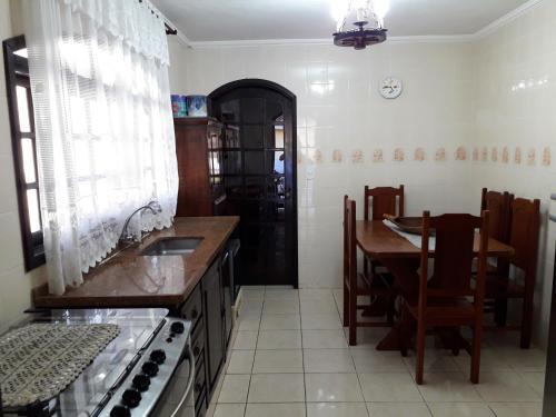 a kitchen with a table and a sink and a stove at Recanto do Ribeirão in Pindamonhangaba