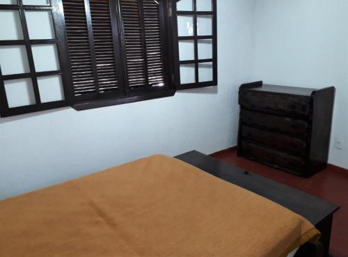 a room with a bed and a dresser and windows at Recanto do Ribeirão in Pindamonhangaba