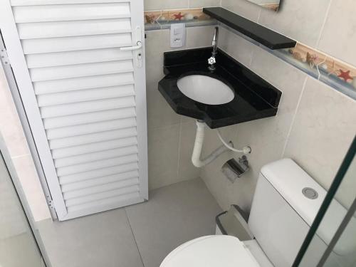 a small bathroom with a toilet and a sink at Kitnet in Ubatuba