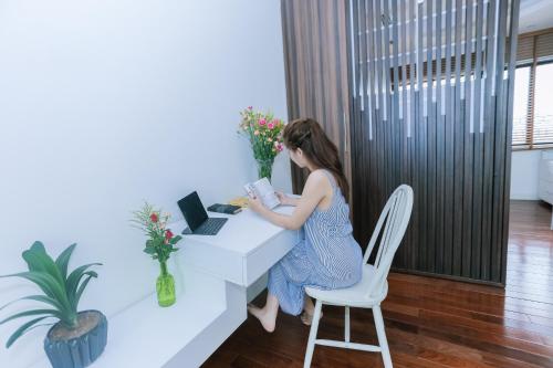 a woman sitting at a desk with a laptop at HNC Premier Hotel & Residences in Hanoi