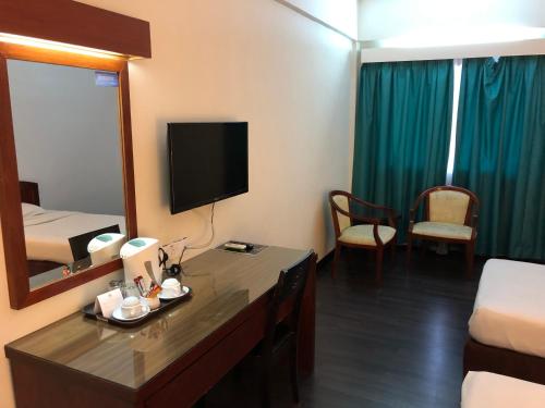 a hotel room with a bed and a desk with a mirror at Hotel Seri Malaysia Alor Setar in Alor Setar