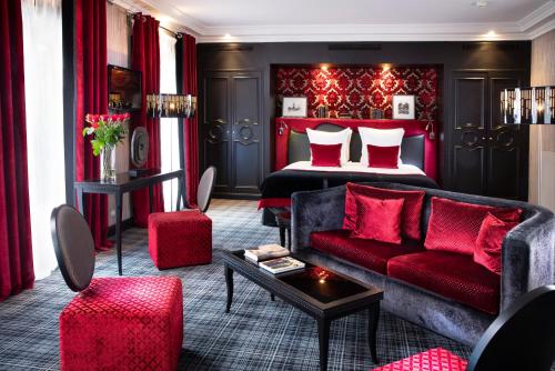 uma sala de estar com uma cama e um sofá vermelho em Edouard 7 Paris Opéra em Paris