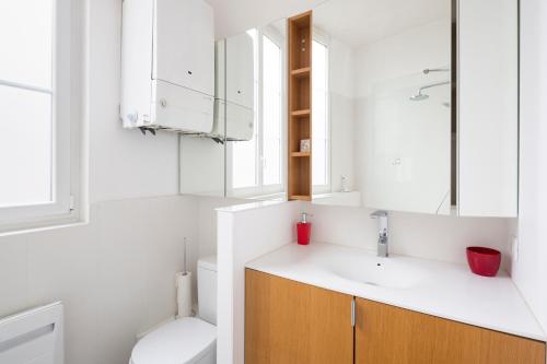 La salle de bains blanche est pourvue d'un lavabo et de toilettes. dans l'établissement L'Esquisse by Cocoonr, à Nantes