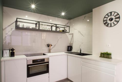 une cuisine avec des placards blancs et une horloge murale dans l'établissement L'Opéra - Bel appartement au pied du Capitole, à Toulouse