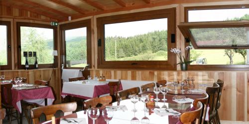 een eetkamer met tafels, stoelen en ramen bij Gîtes du Kreuzweg in Le Hohwald