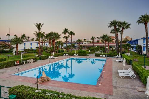 una piscina en un complejo con palmeras y edificios en Parador de Benicarló, en Benicarló