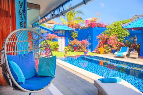 a wicker chair sitting next to a swimming pool at Villa Majorelle Bali in Seminyak