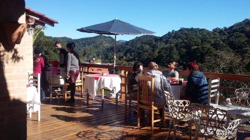 a group of people sitting around a table on a deck at Pousada Pinhalense in Santo Antônio do Pinhal