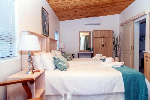 Un dormitorio con una gran cama blanca y una lámpara en Kalahari Camelthorn Guesthouse and Camping, en Askham
