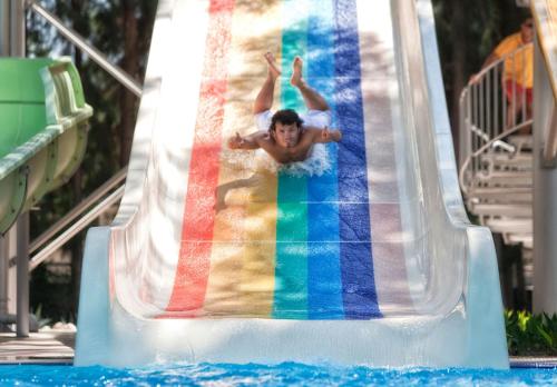 a young boy sliding down a water slide in a pool at Akka Antedon Hotel - Premium Ultra All Inclusive in Beldibi