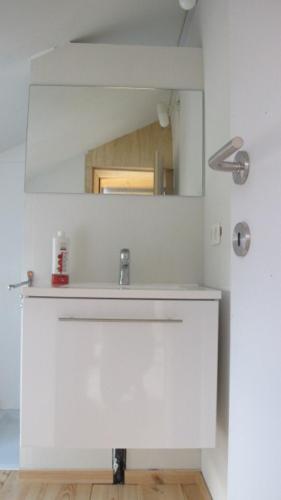 uma casa de banho com um lavatório branco e um espelho. em Huize Maeterlinck em Gent