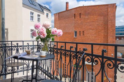 a table with a vase of pink flowers on a balcony at Apartament Sensual SAUNA&JACUZZI Poznań Stare Miasto in Poznań