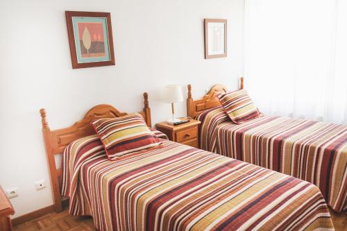 a bedroom with two beds with striped sheets at Piso turístico Belisa in Lerma