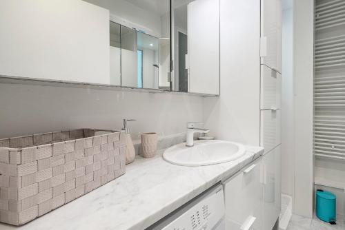 uma casa de banho branca com um lavatório e um espelho em Immeuble Villa PIRON em Nice
