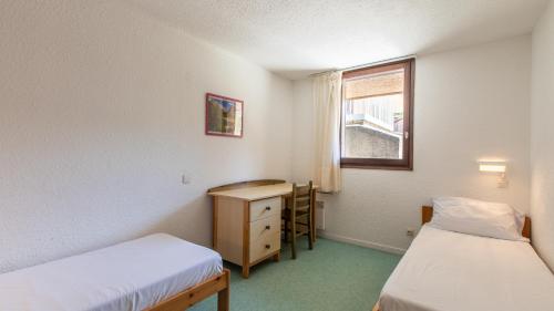 a room with two beds and a desk and a window at Vacancéole - Résidence Les Gorges Rouges in Guillaumes