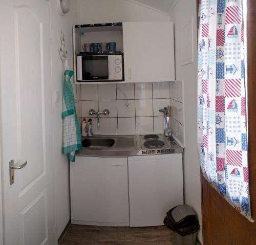 a small kitchen with a sink and a microwave at Oázis Apartman in Szántód