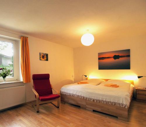 a bedroom with a bed and a red chair at Ferienwohnung am Dümmer See in Dümmer