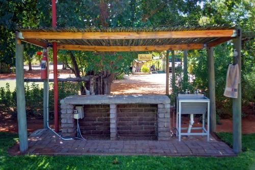 a brick fireplace with a wooden canopy and a table at Kalahari Camelthorn Guesthouse and Camping in Askham