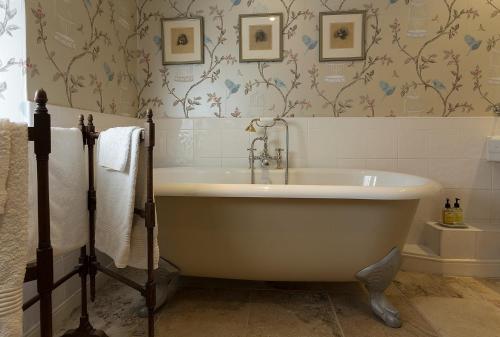 a white bath tub in a bathroom with wallpaper at Thistleyhaugh farmhouse in Longhorsley
