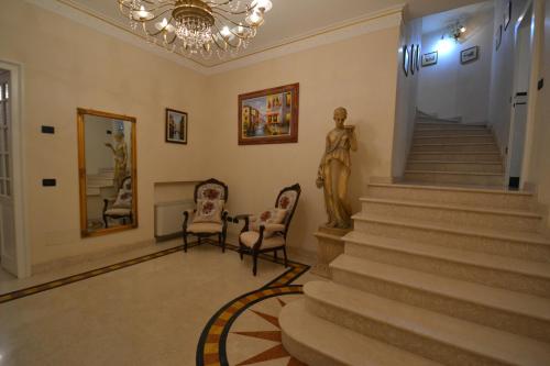 a lobby with two chairs and stairs with a statue at Villa Rina Deluxe and Cottage in Porto Ceresio