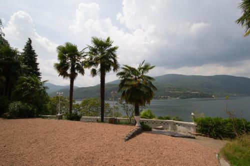 a park with palm trees and a view of the water at Villa Rina Deluxe and Cottage in Porto Ceresio
