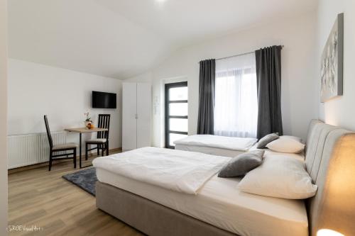 a bedroom with two beds and a table and chair at Apartmani Gundulić in Osijek