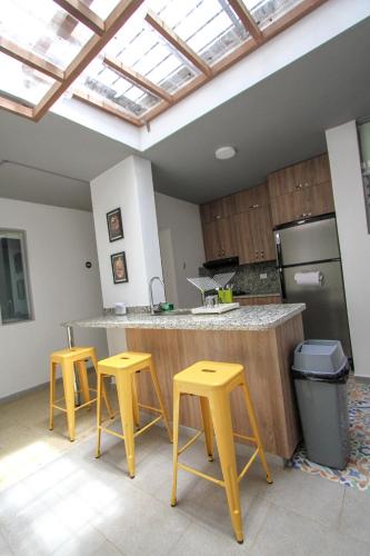 a kitchen with yellow stools and a counter with a sink at Casa Tuvia in Medellín