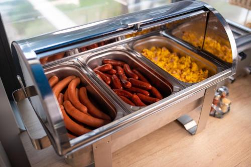 a tray of hot dogs and other food in a buffet at Hotel Solero in Siófok
