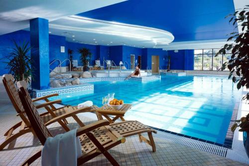 uma grande piscina com cadeiras e uma mulher ao fundo em Actons Hotel Kinsale em Kinsale