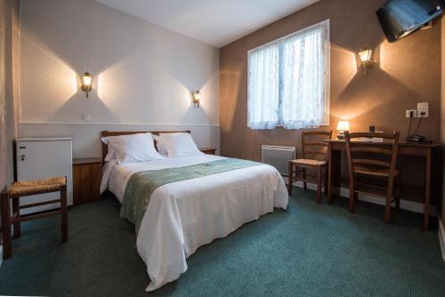 ein Hotelzimmer mit einem Bett, einem Tisch und Stühlen in der Unterkunft Les Ambassadeurs Hotel - Logis in Souillac