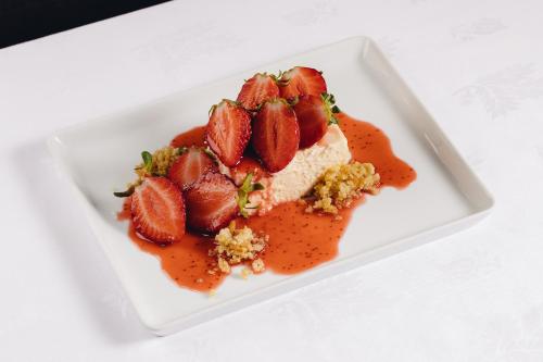a piece of cake with strawberries on a white plate at Pateo dos Solares Charm Hotel in Estremoz