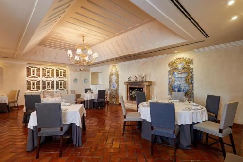 a dining room with tables and chairs and a chandelier at Pateo dos Solares Charm Hotel in Estremoz