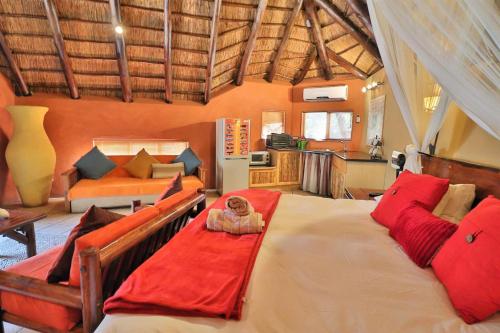 a bedroom with a large bed with red pillows at Manzini Chalets in Marloth Park