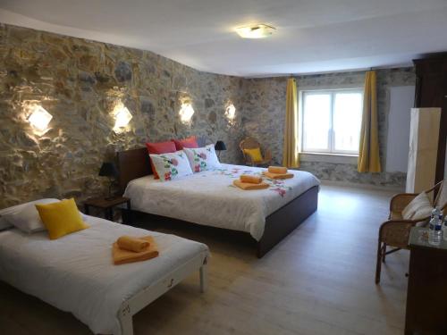 a bedroom with two beds and a stone wall at Chambres d'hôtes Les Gragniotes in Tournissan