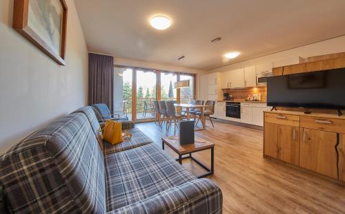 a living room with a couch and a tv and a kitchen at AlpenParks Hotel & Apartment Sonnleiten in Saalbach Hinterglemm