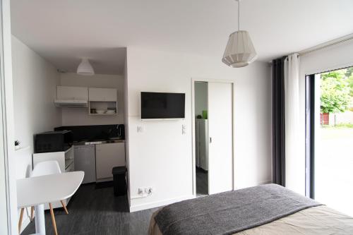 une chambre blanche avec un lit et une cuisine dans l'établissement Studio indépendant chez l’habitant au calme, à Dompierre-sur-Yon